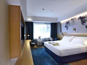 um quarto de hotel com uma cama grande e uma televisão em Kyriad Marvelous Hotel Changsha Furong Plaza Railway Station em Changsha