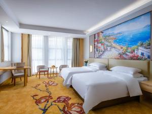 une chambre d'hôtel avec 3 lits et un tableau mural dans l'établissement Vienna International Hotel Fujian Quanzhou Jinjiang Airport, à Jinjiang