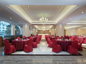 Longnan的住宿－维也纳国际酒店赣州龙南迎宾大道店，一个带红色桌椅的大型宴会厅
