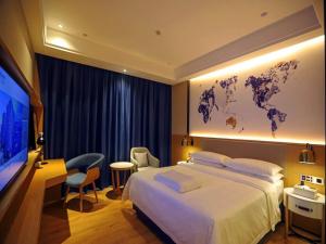 a hotel room with a large bed and a flat screen tv at Kyriad Hanzhong Railway Station in Hanzhong