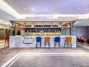 eine Bar in einem Restaurant mit vier blauen und orangefarbenen Stühlen in der Unterkunft Kyriad Marvelous Hotel Chaozhou Fortune Central in Chaozhou