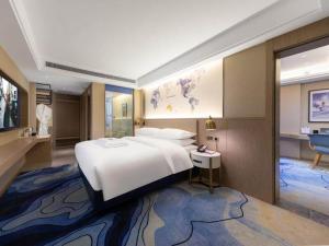 Un dormitorio grande con una cama blanca grande y una mesa. en Kyriad Marvelous Hotel Heyuan Longchuan, en Longchuan
