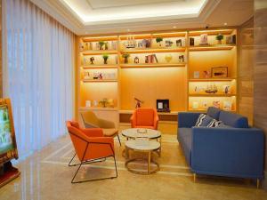 sala de estar con sofá azul y sillas de color naranja en Kyriad Marvelous Hotel Shantou Railway Station, en Shantou