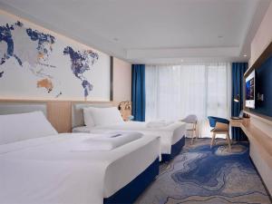 a hotel room with three beds and a map of the world at Kyriad Hotel Zhongshan University of Science and Technology in Zhongshan