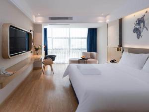 a hotel room with a large bed and a tv at Kyriad Marvelous Hotel Shenzhen Longhua Mission Hills Bamboo Village Subway Station in Bao'an