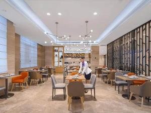 a woman standing at a table in a restaurant at Kyriad Marvelous Hotel Jingxian in Jing