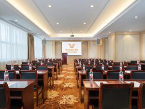 une salle de conférence avec des tables et des chaises ainsi qu'un podium dans l'établissement Vienna International Jiangsu Wuxi Taihu Expo Center, à Wuxi