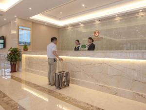 Een man met een koffer op een vliegveld. bij Vienna SanHao Hotel Jiangsu Danyang Jinying in Danyang