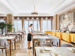Una mujer está de pie en un comedor en Vienna International Hotel Zhejiang Wenzhou Ruian Tangxia, en Ruian