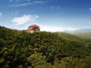 a building on the top of a hill with trees at Kyriad Marvelous Hotel Yiyang Ziyang in Yiyang