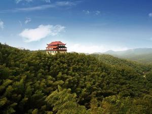 a building on the top of a hill with trees at Kyriad Marvelous Hotel Yiyang Ziyang in Yiyang