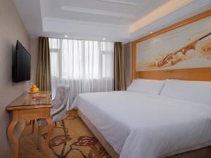 a hotel room with a bed and a desk and a bed and a table at Vienna International Hotel Shenzhen Longhua Xikeng Subway Station in Tiantangwei