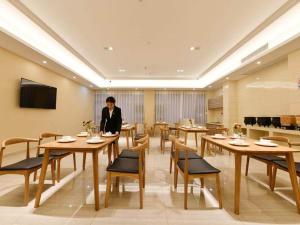 een persoon in een restaurant met tafels en stoelen bij Vienna SanHao Hotel Jiangsu Danyang Jinying in Danyang