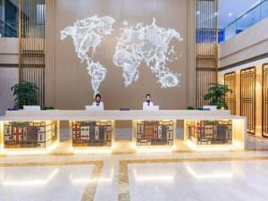 two people in a lobby with a map of the world at Kyriad Marvelous Hotel Shouguang Municipal Government in Shouguang