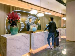 長沙市にあるKyriad Marvelous Hotel Changsha Furong Plaza Railway Stationの職場の窓口に立つ男