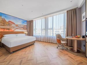 een hotelkamer met een groot bed en een bureau bij Vienna Hotel Jiangyin Zhouzhuang in Jiangyin
