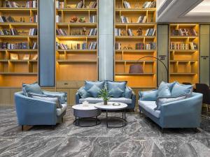 uma biblioteca com dois sofás e uma mesa e prateleiras em Kyriad Marvelous Hotel Henan Xinyang Pingqiao Plaza em Xinyang