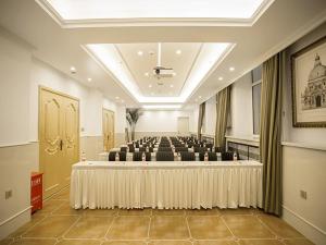 ハルビン市にあるVienna Hotel Harbin Train Station Jianguo Streetのテーブルと椅子が備わる広い客室です。