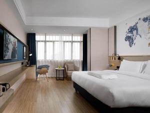 ein Hotelzimmer mit einem großen Bett und einem Schreibtisch in der Unterkunft Kyriad Marvelous Hotel Foshan Nanzhuang Taobo Avenue in Foshan