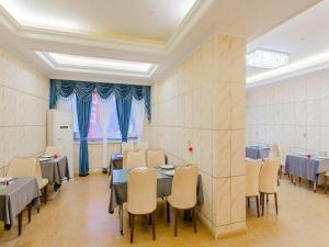 a dining room with tables and chairs and blue curtains at Vienna Classic Hotel Mudanjiang Railway Station in Mudanjiang