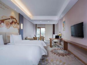 Longnan的住宿－维也纳国际酒店赣州龙南迎宾大道店，酒店客房设有两张床和一台平面电视。