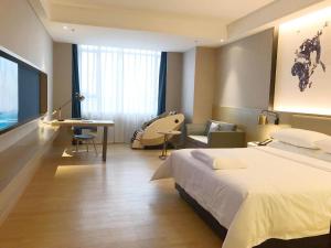 a hotel room with a large bed and a desk at Kyriad Marvelous Hotel Huizhou Boluo Yuanzhou in Boluo