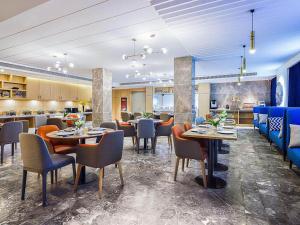 um restaurante com mesas e cadeiras num quarto em Kyriad Marvelous Hotel Weihai Happy Gate Weigao Plaza em Weihai