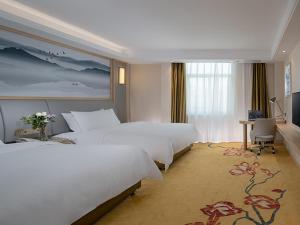 a large hotel room with two beds and a desk at Vienna Classic Hotel Shenzhen Pingshan Bihu Hotel in Longgang