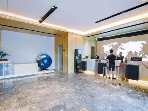 a person standing at a counter in a hotel lobby at Kyriad Marvelous Hotel Weihai Happy Gate Weigao Plaza in Weihai