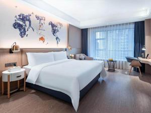 a large white bed in a hotel room with a map of the world at Kyriad Marvelous Hotel Guizhou Dujun Center Wanda Plaza in Duyun