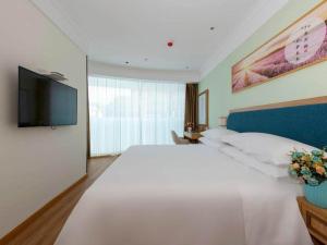 a bedroom with a large white bed and a flat screen tv at Vienna SanHao Hotel Danyang Houxiang in Matunlijia