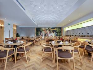 un restaurante con mesas y sillas de madera y una pintura en Vienna International Hotel Chongqing North Station en Chongqing