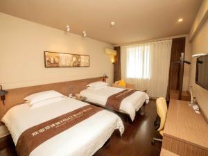 a hotel room with two beds and a television at Jinjiang Inn Select Yangzhou Slender West Lake Siwangting Road in Yangzhou