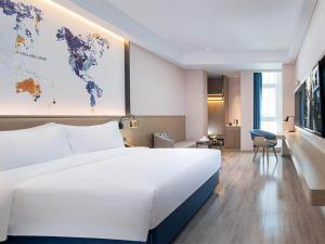 a large white bed in a hotel room with a map on the wall at Kyriad Marvelous Hotel Daya Bay BYD Technology Park in Huizhou