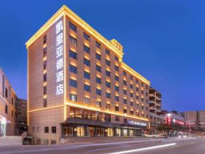 Un gran edificio en una calle de la ciudad por la noche. en Kyriad Marvelous Hotel Heyuan Longchuan, en Longchuan