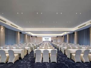 a conference room with rows of chairs and a screen at Kyriad Marvelous Hotel Guilin Quanzhou in Quanzhou