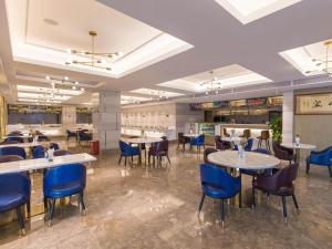 a dining room with tables and blue chairs at Kyriad Marvelous Hotel Shenzhen Linheng Plaza Liuyue Subway Station in Liantang
