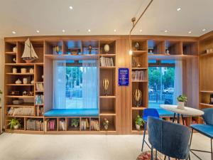 a library with a blue bench and bookshelves at Kyriad Marvelous Hotel Shanghai Daning International Plaza in Shanghai