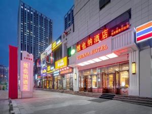 un groupe de bâtiments avec des panneaux de néons la nuit dans l'établissement Vienna Hotel Harbin West Railway Station Wanda Plaza, à Harbin