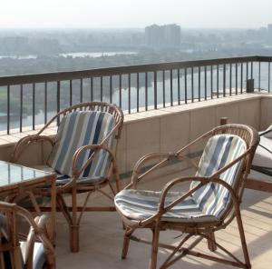 2 Stühle und ein Tisch auf dem Balkon in der Unterkunft Cairo, Pyramids and Nile River View Luxury Apartment, Maadi Corniche in Kairo