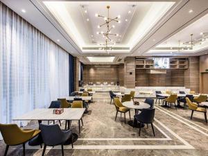 Un restaurante con mesas y sillas en una sala. en Kyriad Marvelous Hotel Haifeng, en Haifeng