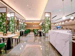 長沙市にあるKyriad Marvelous Hotel Changsha Furong Plaza Railway Stationのテーブルと緑の椅子が備わるレストラン、バー