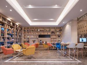 una biblioteca con sillas, mesas y estanterías coloridas en Kyriad Marvelous Hotel Haikou Free Trade Zone, en Haikou