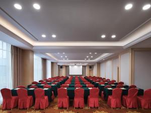 uma sala de conferências com cadeiras vermelhas e um ecrã em Vienna International Hotel Nanchang Qingshan Lake Wanda Plaza em Nanchang