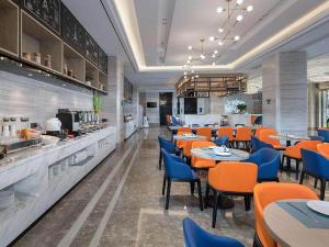 a restaurant with tables and chairs and a kitchen at Kyriad Marvelous Hotel Shenzhen Longhua District Qinghu Subway Station in Tiantangwei