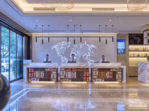 three people sitting at a desk in a library with a world map at Kyriad Marvelous Hotel Hengyang Changning in Changning