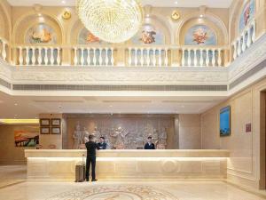 a man standing at a counter in a hotel lobby at Vienna hotel Hunan Shaoyang Longhui Bus Station in Longhui