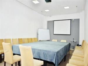 a meeting room with a table and chairs and a screen at Jinjiang Inn Changchun Railway Station New Branch in Changchun