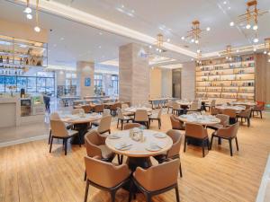 a restaurant with tables and chairs and a bar at Kyriad Marvelous Hotel Zhongshan South District Conference Centre in Huancheng