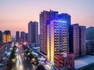 Un edificio alto con luces encendidas en una ciudad. en Kyriad Marvelous Hotel Haifeng, en Haifeng